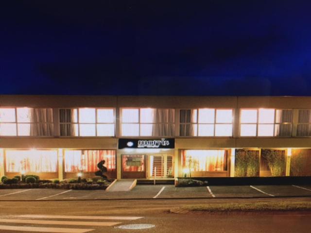 un bâtiment éclairé avec un magasin devant lui dans l'établissement Hôtel Morris, à Le Pont-de-Beauvoisin