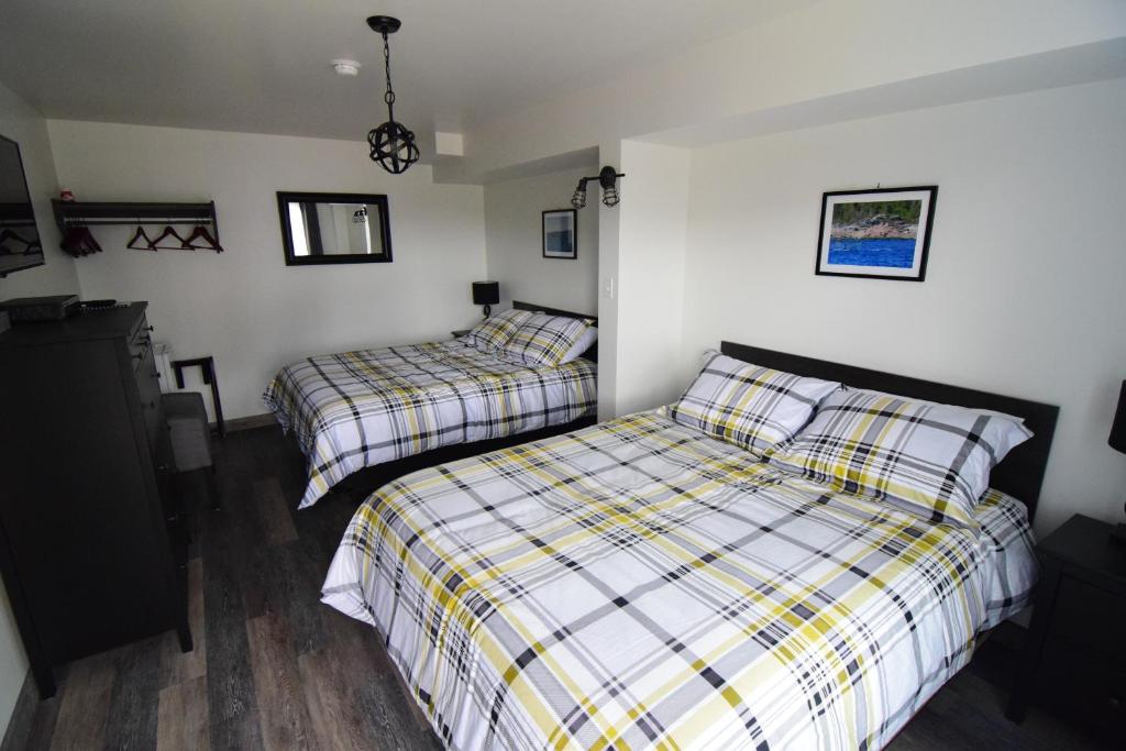 een slaapkamer met 2 bedden en geruite lakens bij Mon Coin de Pays in Sacré-Coeur-Saguenay