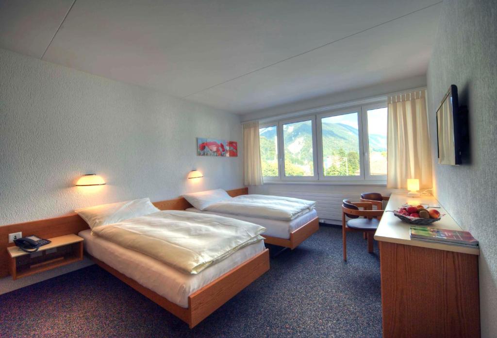 Cette chambre comprend 2 lits et une fenêtre. dans l'établissement Hôtel Oasis, à Moutier