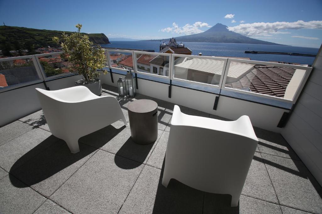 a balcony with white chairs and a view of the water at Manta Ray Lodge in Horta