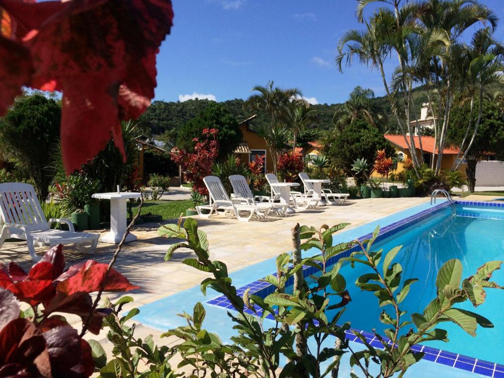 una piscina con sillas y una mesa junto a una casa en Chalés Villa Bella, en Florianópolis