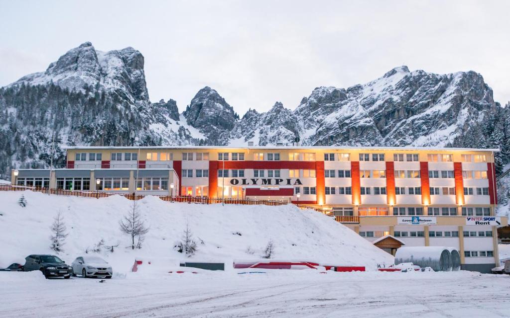 a large building with snow covered mountains in the background at Hotel Olympia in Axamer Lizum