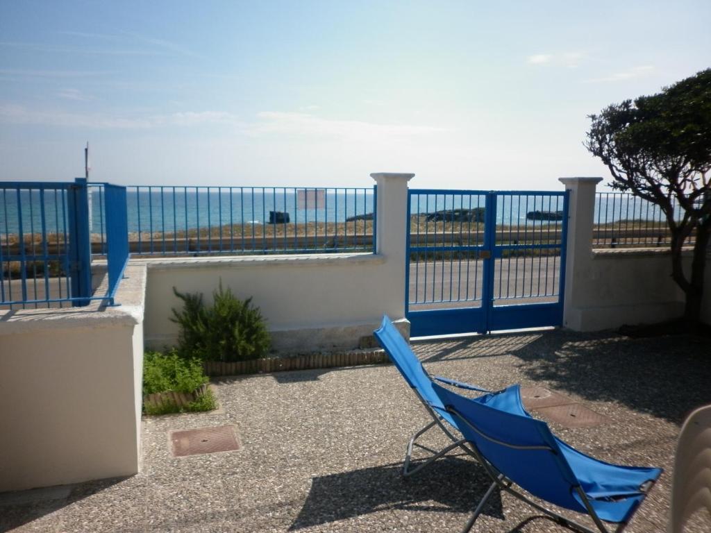 a blue chair on a balcony with the ocean in the background at Villino sul mare in San Foca