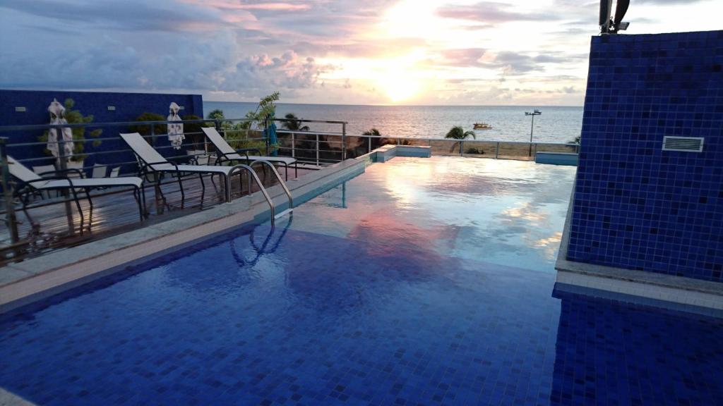 una piscina con sillas y el océano en el fondo en Apartamento Tambau a Beira Mar, en João Pessoa