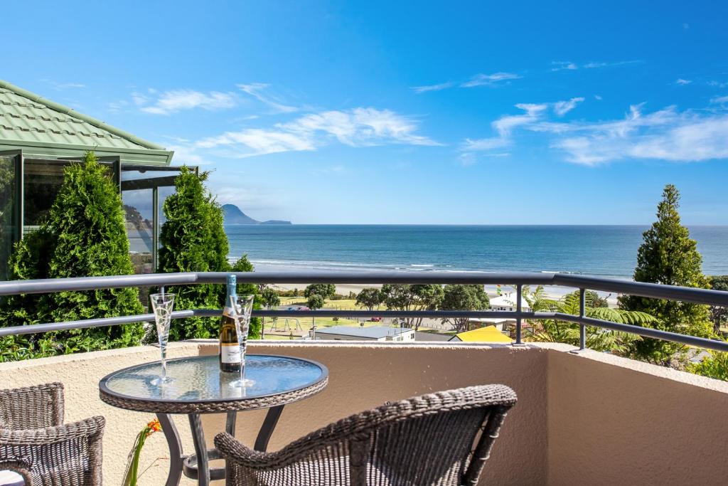 a table on a balcony with a view of the ocean at Ohope Heights in Ohope Beach