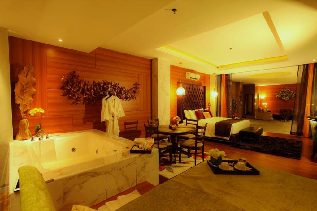 een grote badkamer met een bad en een woonkamer bij Royal Asnof Hotel Pekanbaru in Pekanbaru