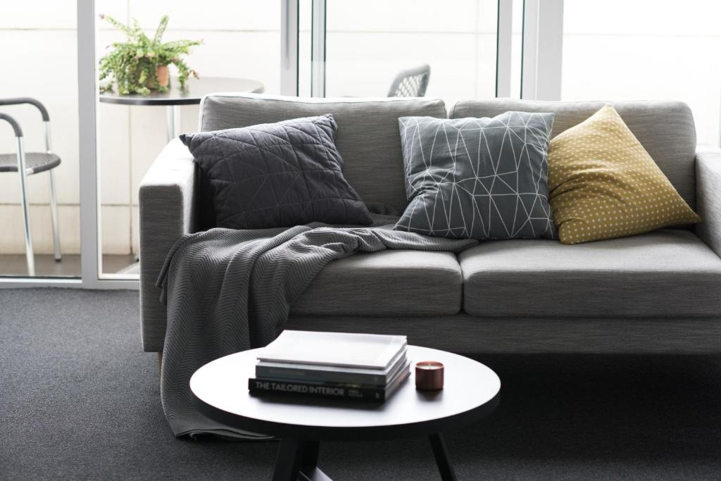 a living room with a couch and a table with books at Tyrian Serviced Apartments Fitzroy in Melbourne