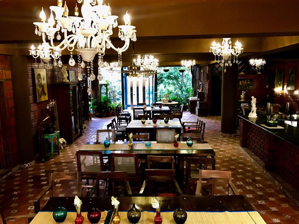 a dining room with chandeliers and tables and chairs at Golden Lotus Bangalore Boutique Suites in Bangalore