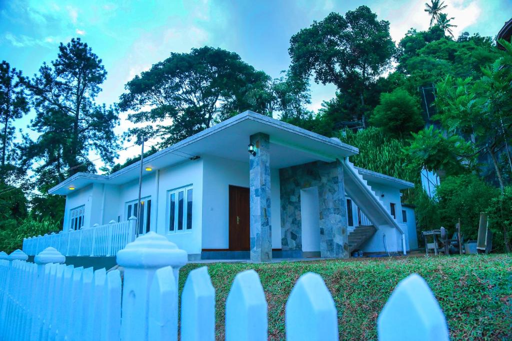 a white fence in front of a small house at Miyura Holiday Bungalow in Kandy