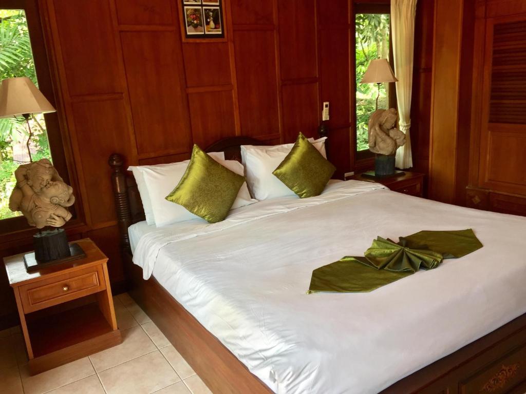 a bedroom with a bed with green bows on it at Baan Laem Noi Villa's in Mae Nam