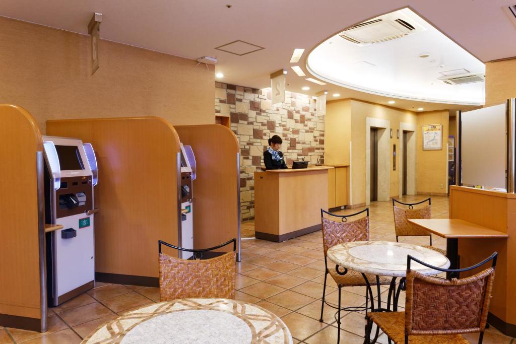 a restaurant with chairs and tables and a person in a counter at R&B Hotel Kumamoto Shimotori in Kumamoto