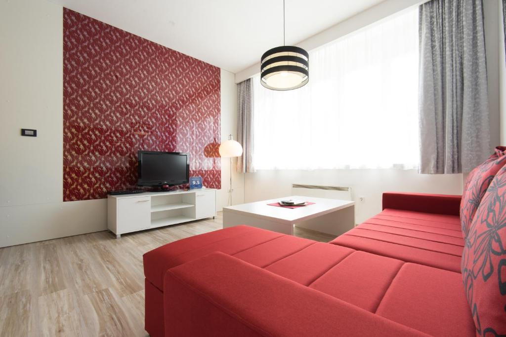 a living room with a red couch and a tv at Apartment Mango in Sarajevo