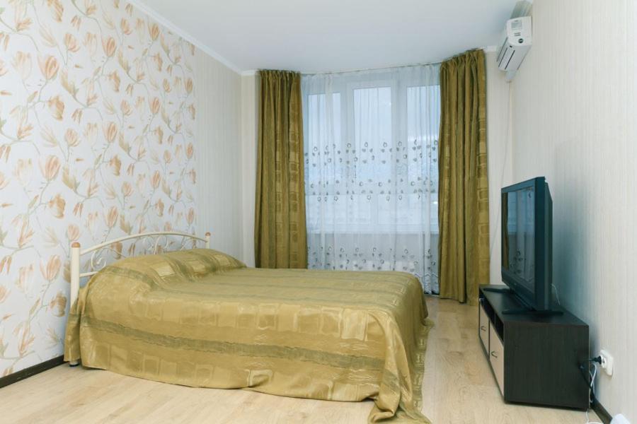 Schlafzimmer mit einem Bett und einem Flachbild-TV in der Unterkunft Apartment on Akhmatovoyi 32/18 in Kiew