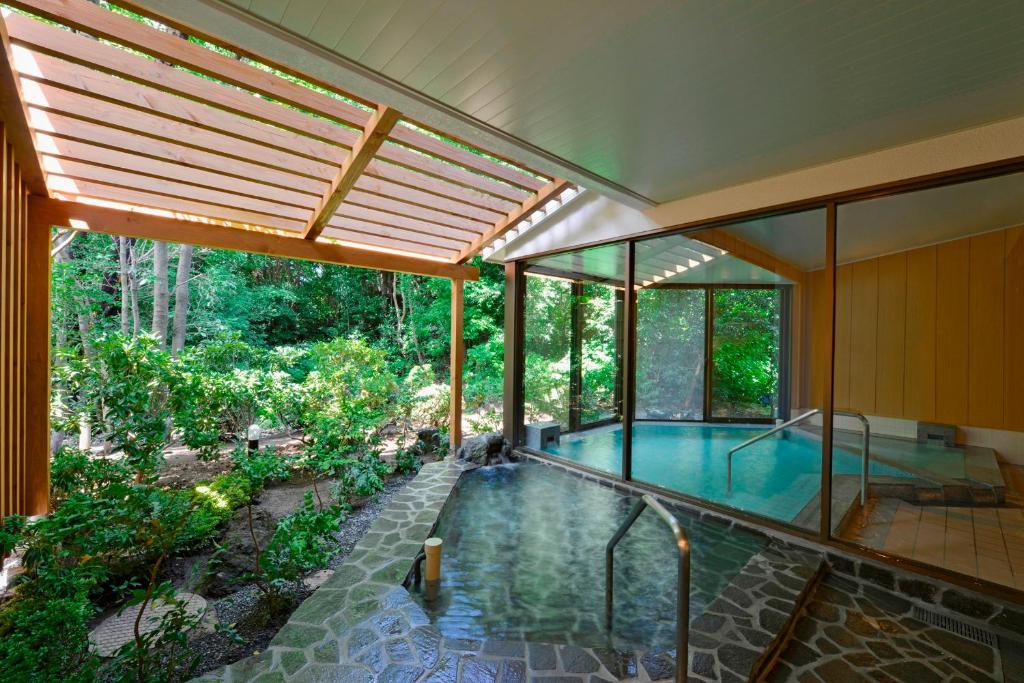 an indoor pool in a house with glass walls at Le Nessa Akazawa in Ito