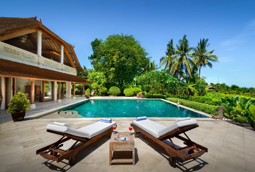 a swimming pool with two lounge chairs next to a house at Villa Bonian Balian in Selemadeg