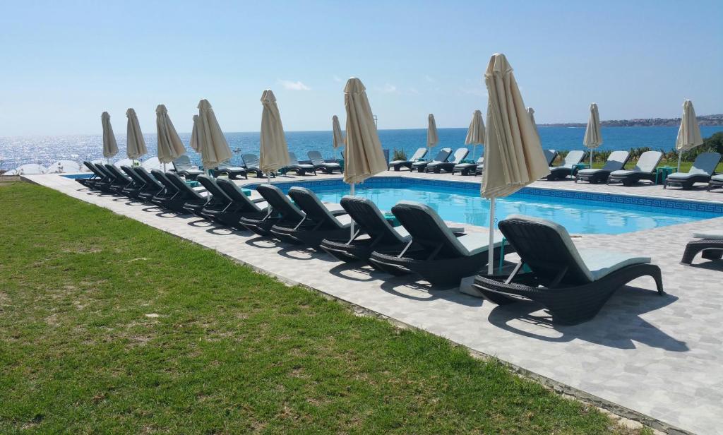 a row of chairs and umbrellas next to a swimming pool at Marica's Boutique Hotel in Paphos