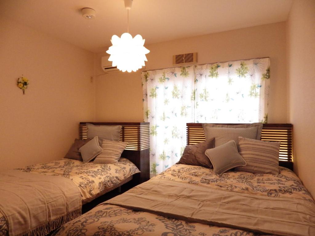 Un dormitorio con 2 camas y una ventana con una lámpara de araña. en Condominio Mozu 102 en Sakai