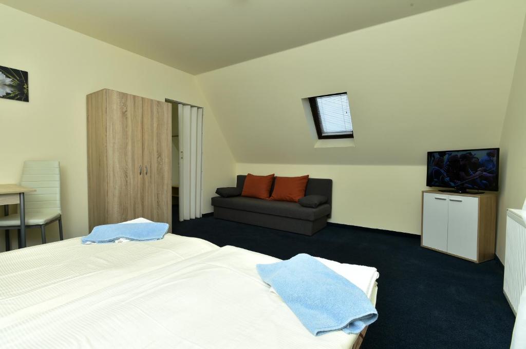 a bedroom with a white bed and a couch at Hotel U Jezírka in Liberec