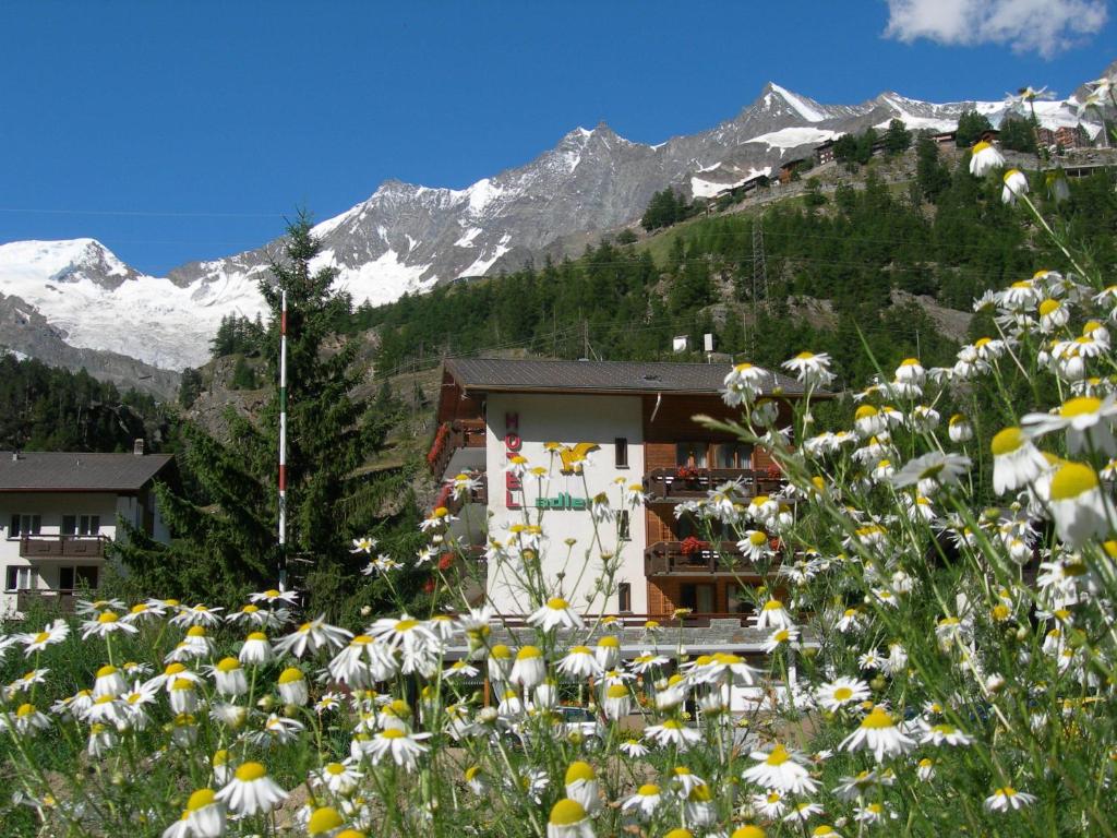 un campo de flores frente a un edificio en Hotel Adler, en Saas-Grund