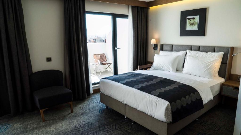 イスタンブールにあるYuksel Istanbul Yenikapı Hotelのベッド1台、椅子、窓が備わる客室です。