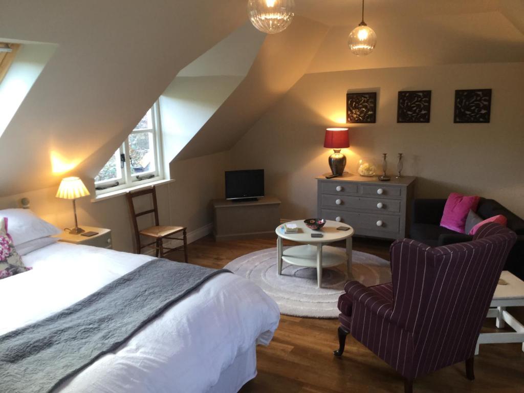a bedroom with a bed and a chair and a table at Field Cottage B&B in Haywards Heath