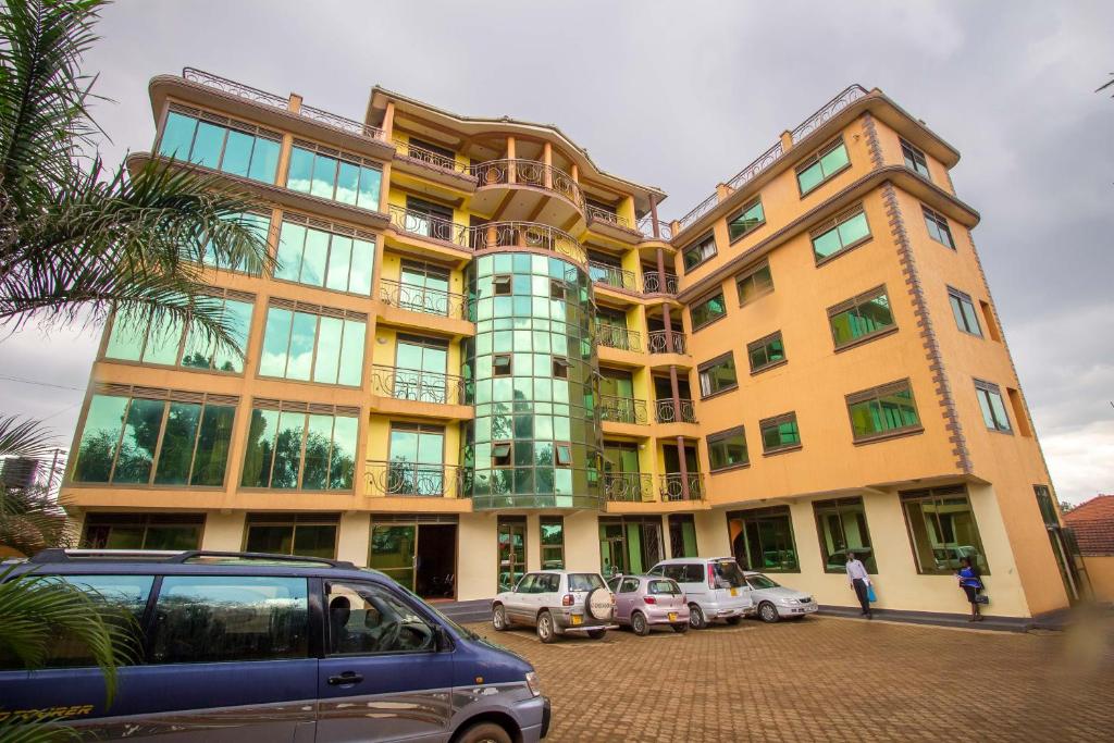 un grand bâtiment avec des voitures garées dans un parking dans l'établissement Minister's Village Hotel, à Kampala