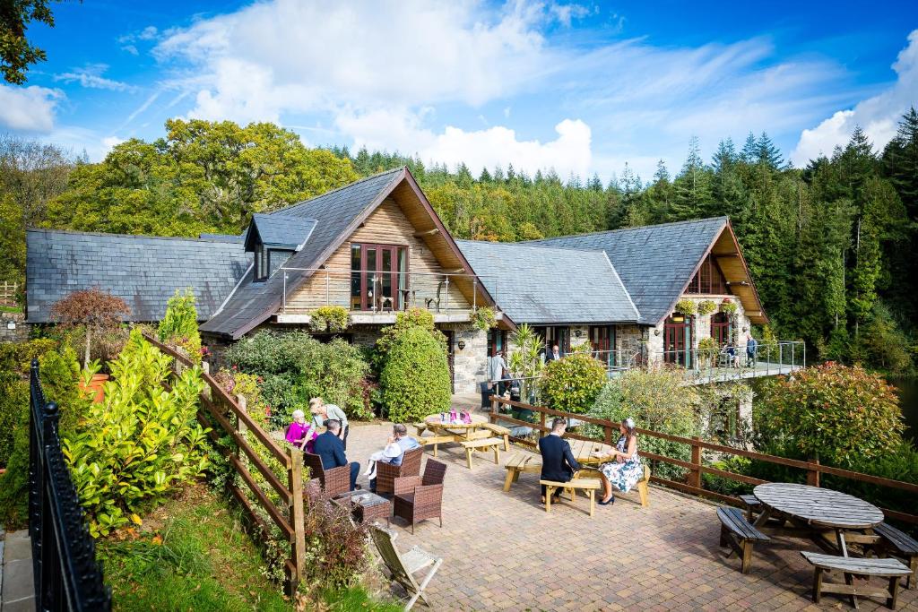 eine Gruppe von Menschen, die auf einer Terrasse vor einem Haus sitzen in der Unterkunft Canada Lodge and Lake in Creigiau