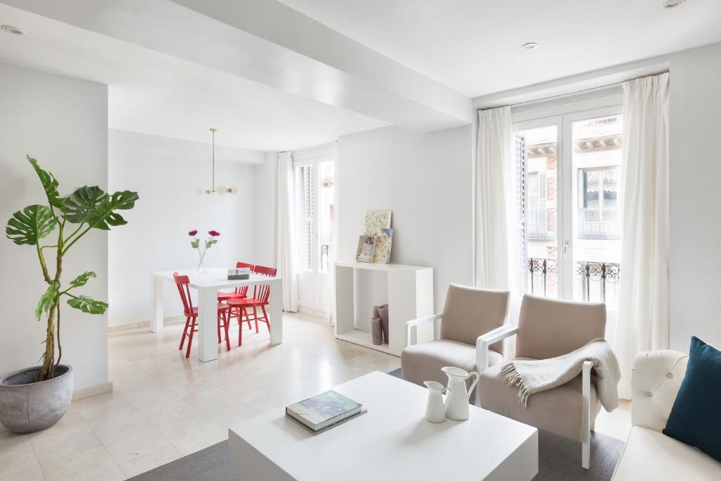 een witte woonkamer met een tafel en stoelen bij Carretas Apartments in Madrid