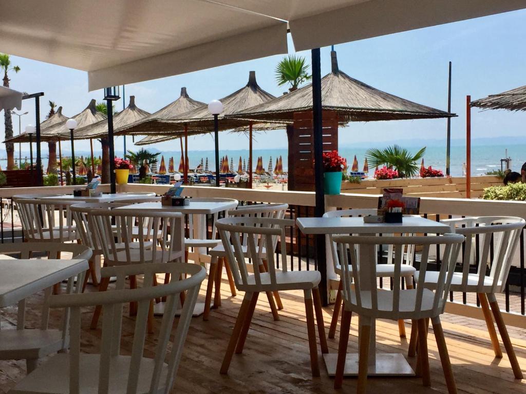 a restaurant with white tables and chairs on the beach at Sunrise Hotel Cameria in Durrës