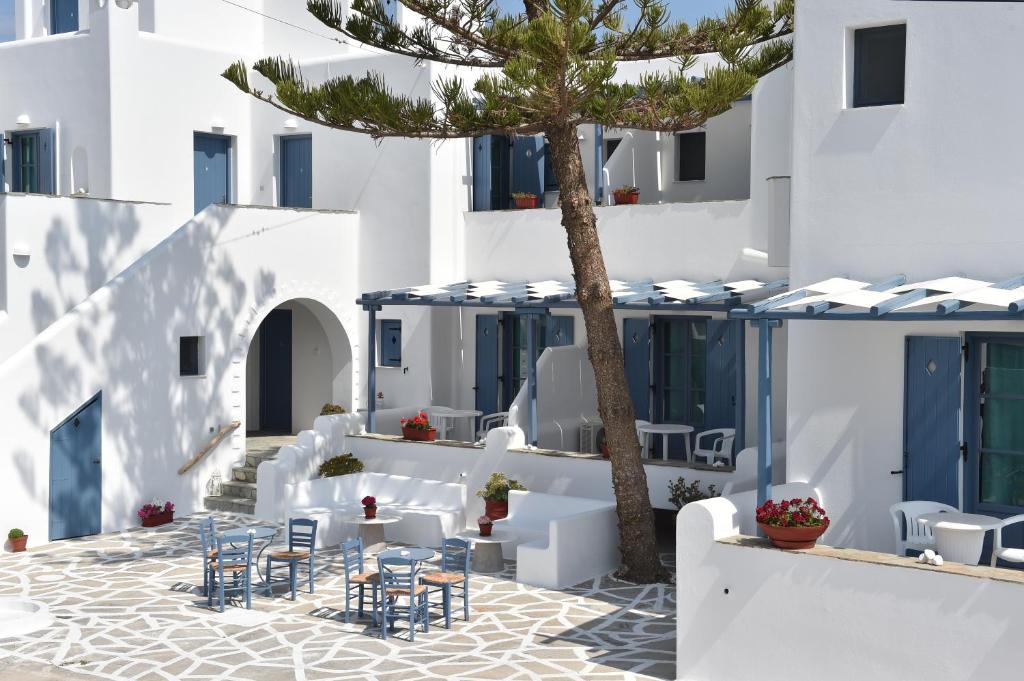 a courtyard with tables and chairs and a palm tree at Magginas Studios in Parikia