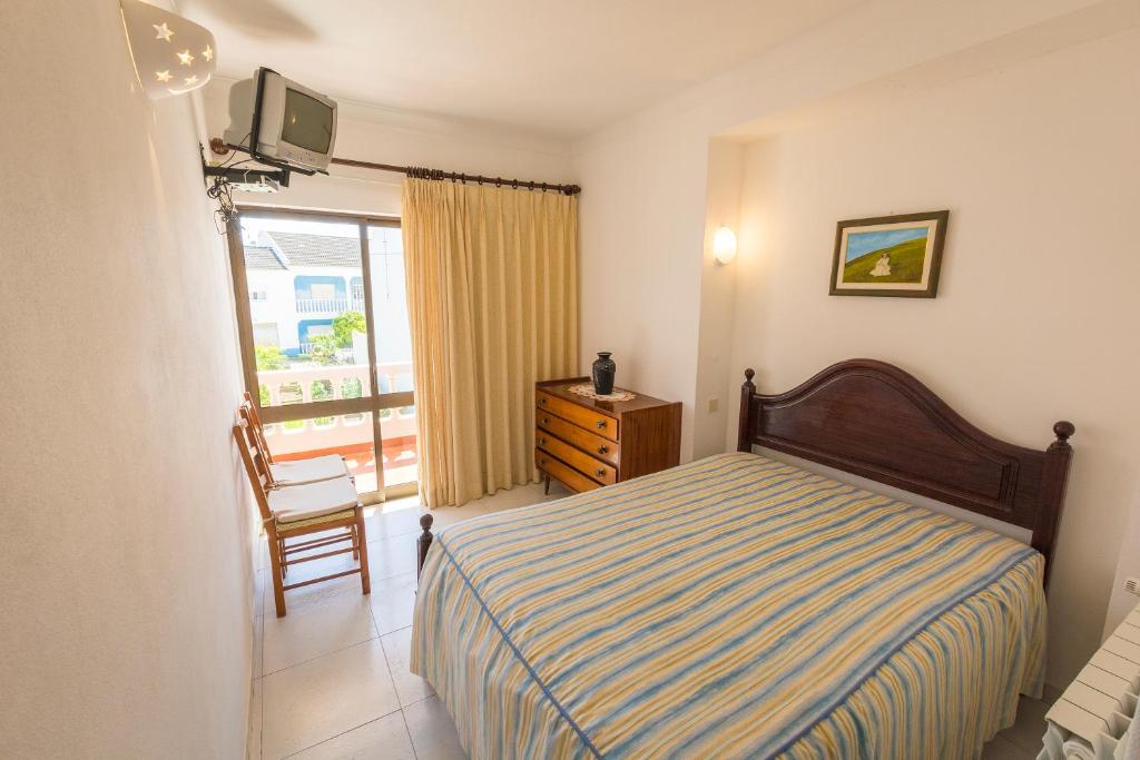 een slaapkamer met een bed, een stoel en een raam bij Guesthouse A Lareira in Aljezur