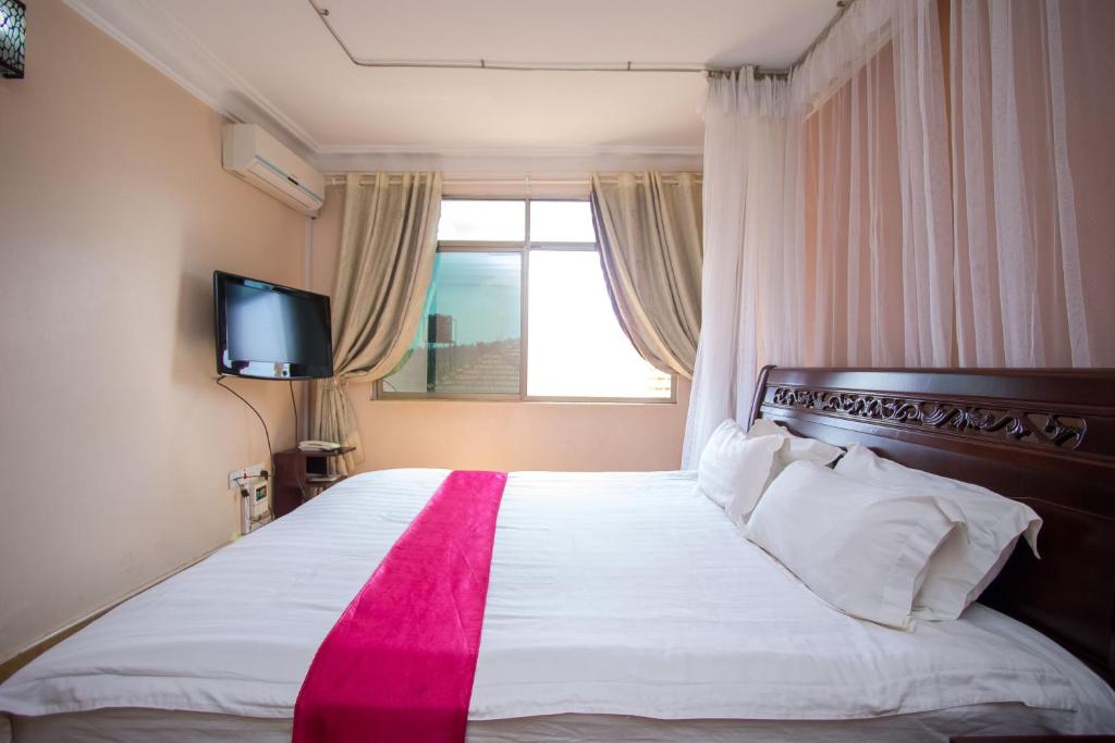 a bedroom with a large white bed with a window at Eight Winx Hotel in Kampala