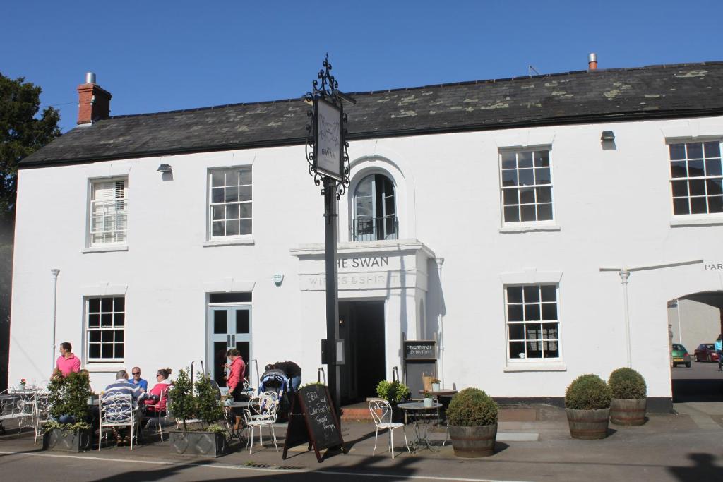 un edificio blanco con gente sentada fuera de él en The Swan, en Wedmore