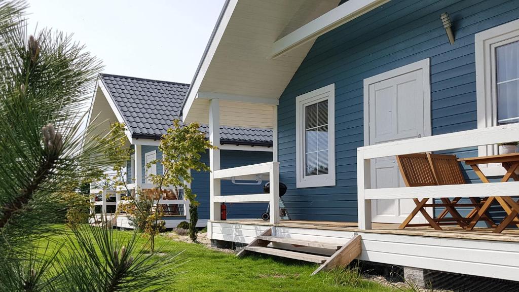 a blue house with a white door and a porch at By The Sea Lodges in Wrzosowo