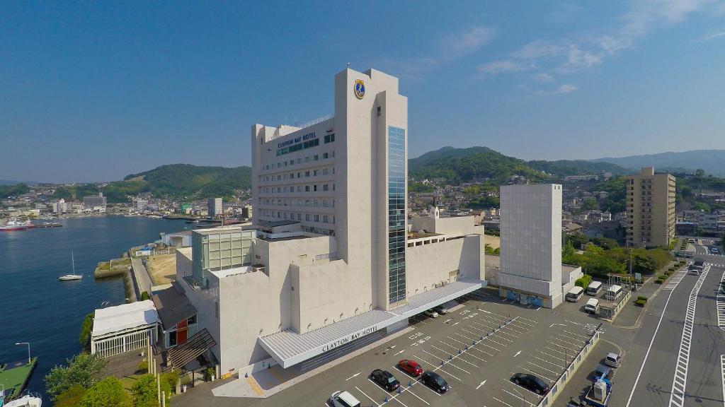 un grand bâtiment blanc à côté d'une étendue d'eau dans l'établissement Clayton Bay Hotel, à Kure