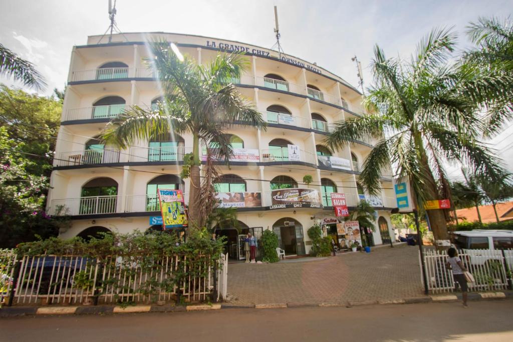 un grande edificio con palme di fronte di La Grand Chez Johnson Hotel Muyenga a Kampala