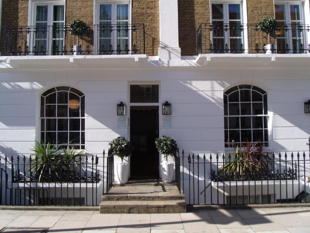 a white house with a black door at Sydney House Chelsea in London