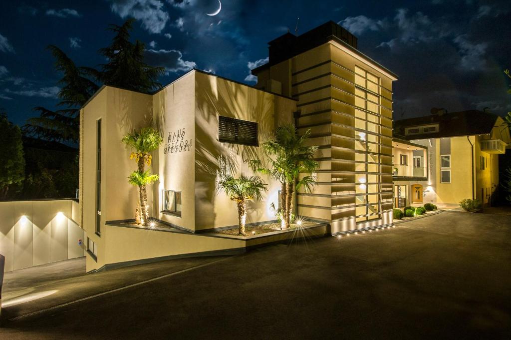 a building with palm trees in front of it at night at Haus Gregori in Caldaro