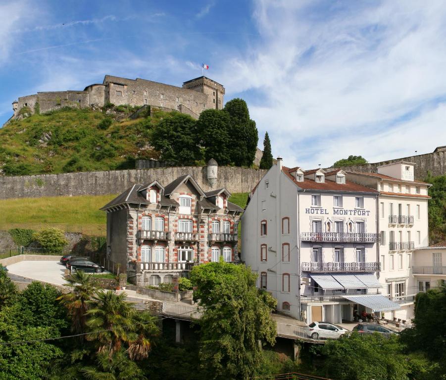 un bâtiment avec un château au sommet d'une colline dans l'établissement Hôtel Montfort, à Lourdes