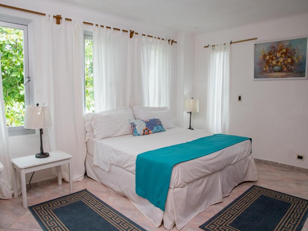 a white bedroom with a bed and two windows at Hotel Neptuno Refugio in Boca Chica