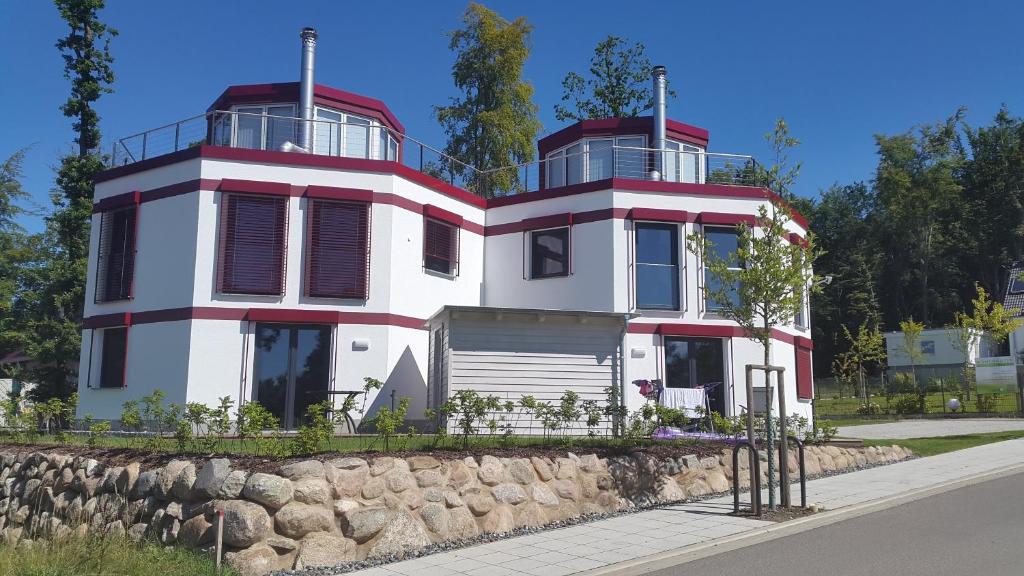 ein großes weißes Haus mit roten Zierleisten an einer Steinmauer in der Unterkunft Ferienhaus Leuchtfeuer in Ostseebad Sellin