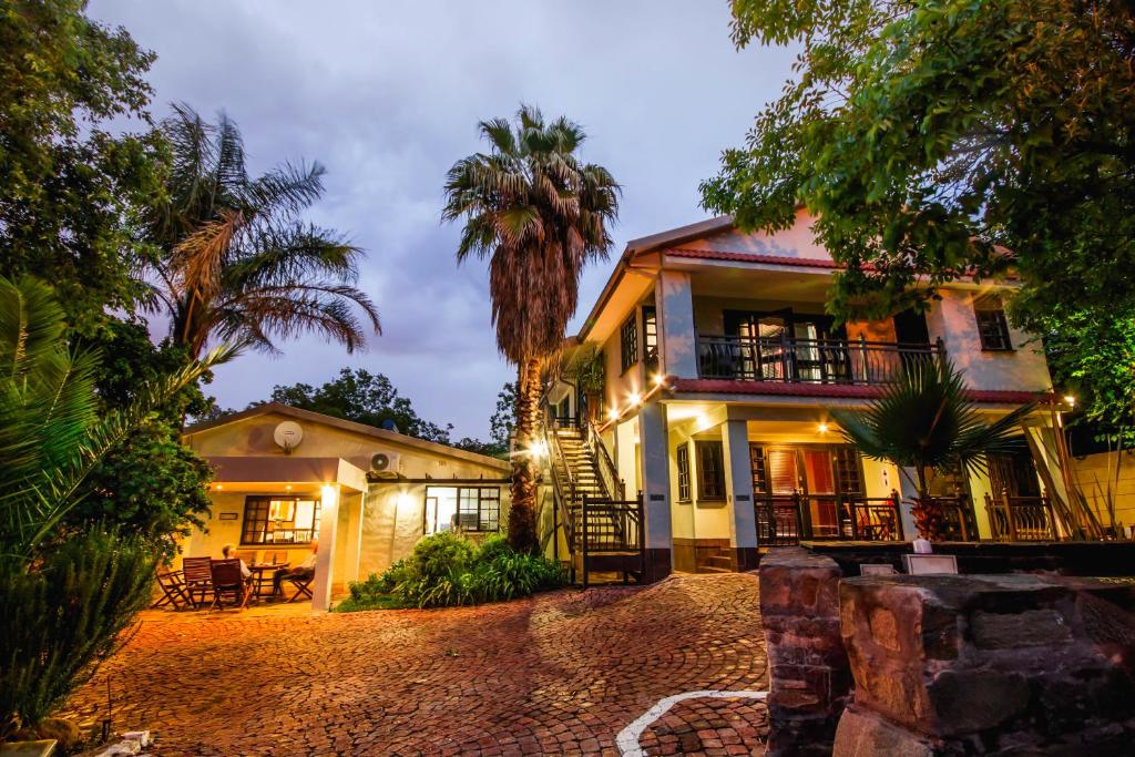 a house with a palm tree in front of it at @The Villa Guest House in Bloemfontein