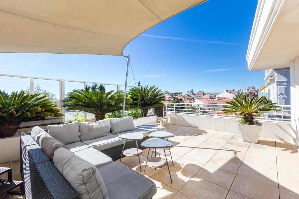 d'une terrasse avec un canapé et des tables sur un balcon. dans l'établissement Superb penthouse in centre of Cannes Stunning views air-conditioning internet Near the Palais 532, à Cannes