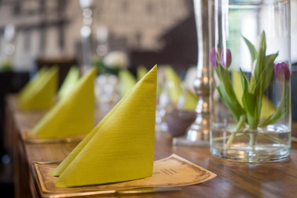 einen Tisch mit gelben Servietten und eine Vase mit Blumen in der Unterkunft Leipziger Hof in Fulda