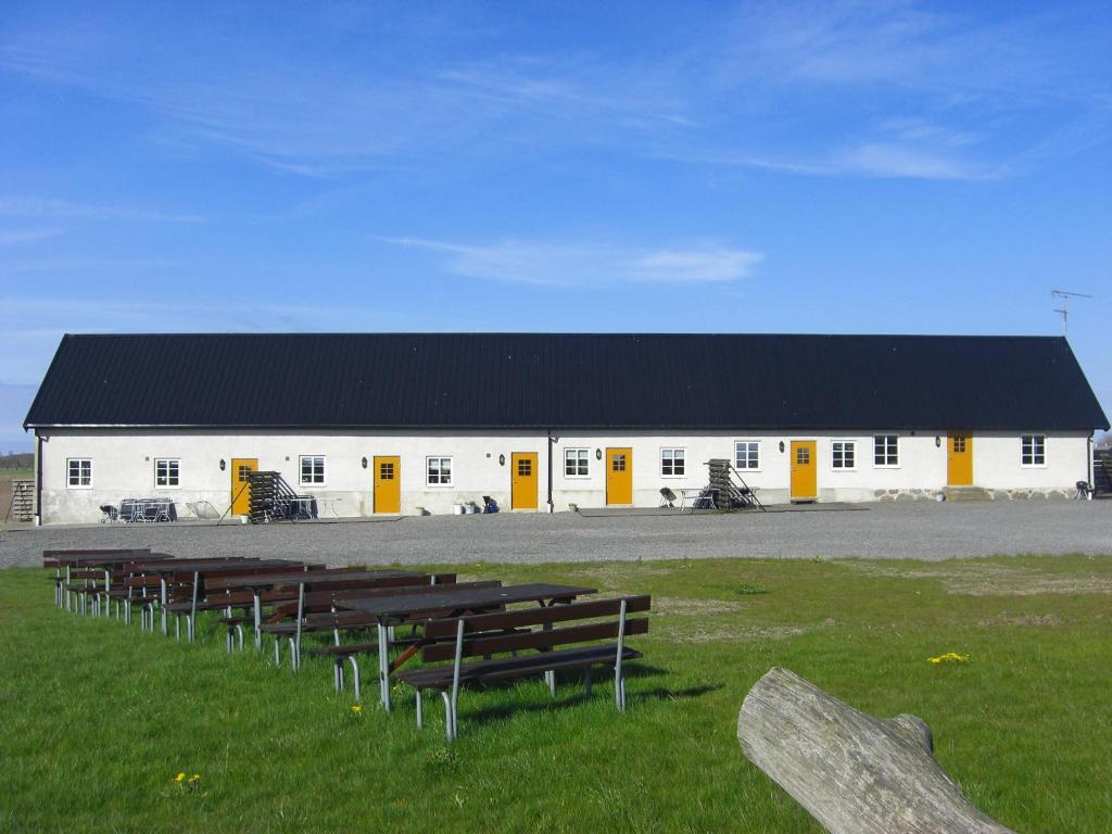 un bâtiment blanc avec un toit noir et une rangée de bancs dans l'établissement Hagestad 47, à Löderup