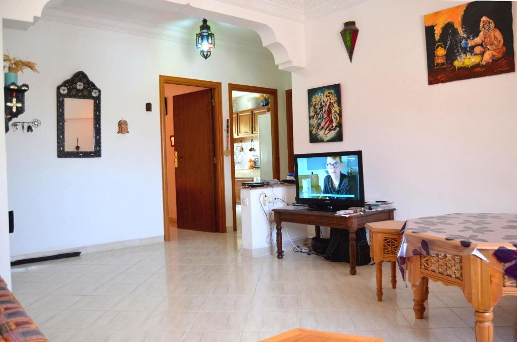 Sala de estar con TV y mesa con mesa en Appartement 400m plage 4eme étage en El Jadida