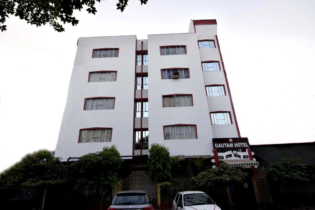 a white building with cars parked in front of it at Gautam Hotel in Varanasi