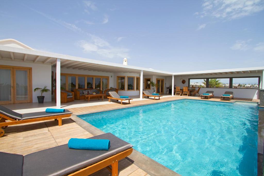 a swimming pool with chairs and a house at Villa Luna Mar in Puerto Calero