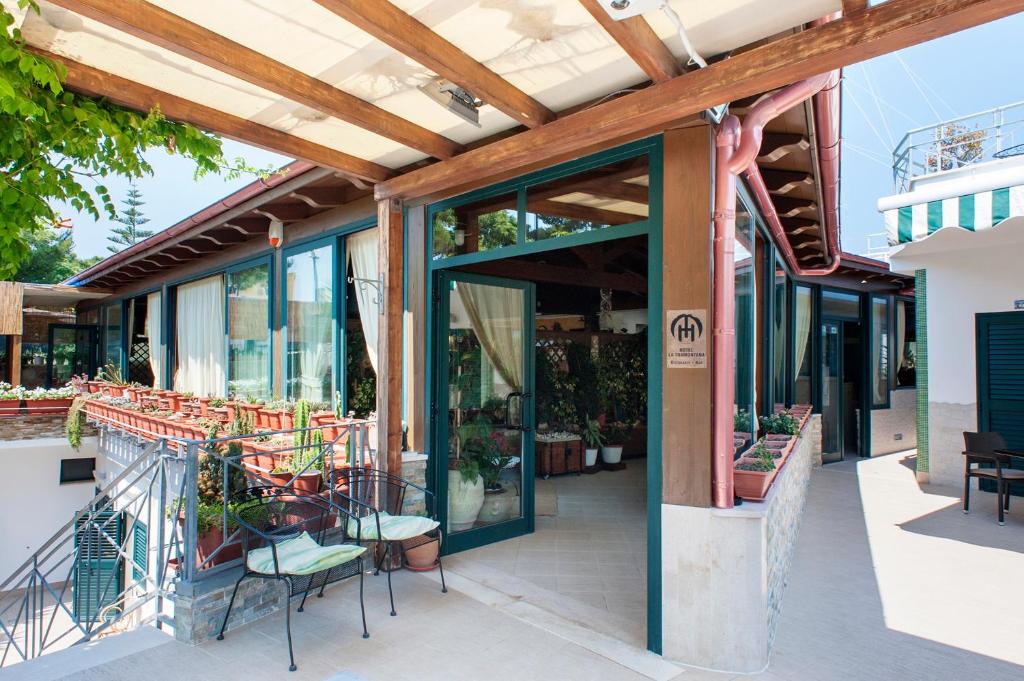 un patio esterno con tavoli, sedie e porte in vetro di Hotel La Tramontana a San Domino