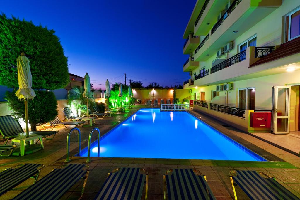 a swimming pool in front of a building at night at Alea Hotel Apartments in Ialysos